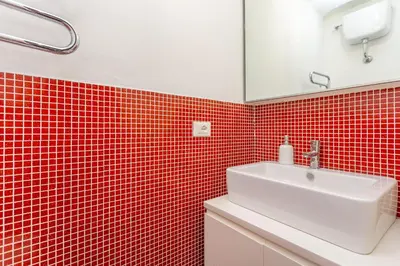 a bathroom with red tiled walls and a white sink at Glam Nest & Garden Colosseum in Rome