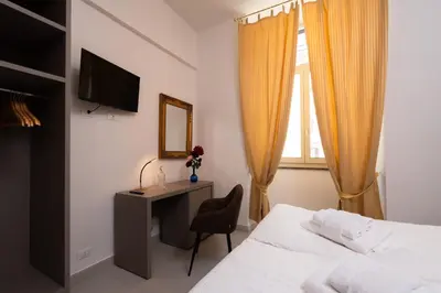 a bedroom with a bed and a desk and a television at Alida Rooms in Rome