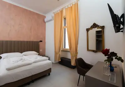 a bedroom with a bed and a desk and a mirror at Alida Rooms in Rome