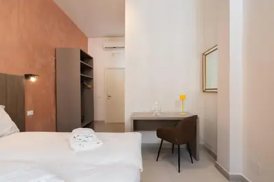 a bedroom with a bed and a desk with a chair at Alida Rooms in Rome
