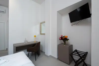 a bedroom with a bed and a desk with a tv on the wall at Alida Rooms in Rome