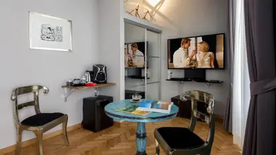 a room with a table and two chairs and a tv at QT Suites Roma in Rome