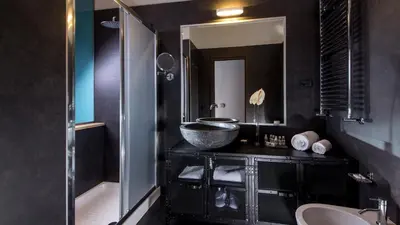 a black bathroom with a sink and a mirror at QT Suites Roma in Rome