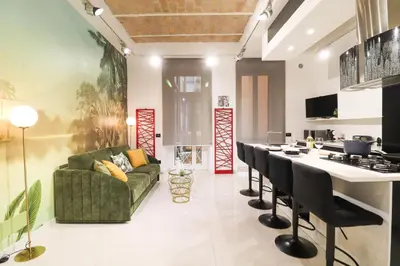 a living room with a green couch and a kitchen at FLORA- Loft Luxury - tra Colosseo e Santa Maria Maggiore - Metro in Rome