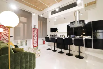 a living room with a green couch and bar stools at FLORA- Loft Luxury - tra Colosseo e Santa Maria Maggiore - Metro in Rome