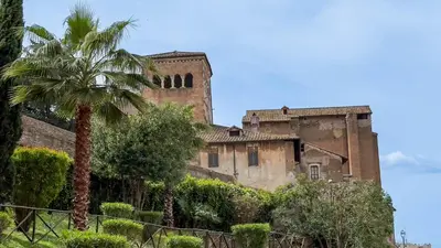 an old castle with a palm tree in front of it at Colosseum Suites - Zen 22 in Rome