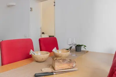 a table with two bowls and two red chairs at Trilussa Spacious Apartment in Rome