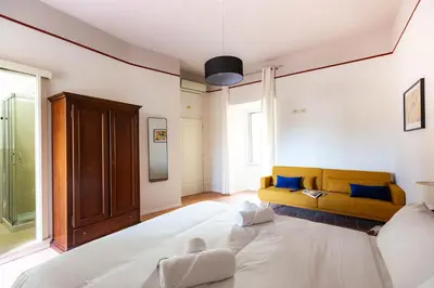 a bedroom with a large white bed and a yellow couch at Colosseum suites apartment - Zen 22 in Rome