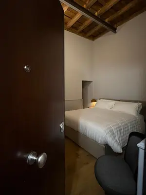 a bedroom with a bed and a door with a chair at Spiriti Home Apartment 3, New Opening Piazza di Pietra in Rome