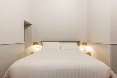 a bedroom with a white bed with two lamps at Spiriti Home Apartment 3, New Opening Piazza di Pietra in Rome