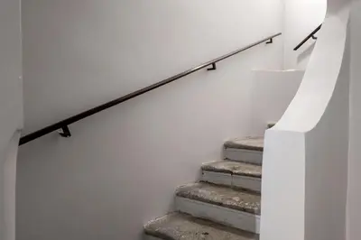 a staircase with a white wall and a rail at The Best Rent - Atmosphere and romance: one-bedroom apartment just steps from the Colosseum in Rome