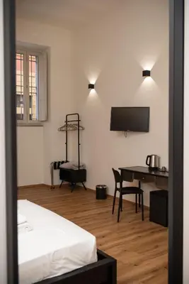 a room with a bed and a desk and a television at By Lina in Trastevere in Rome