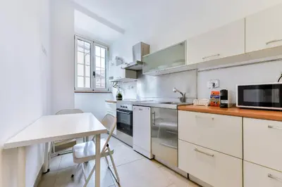 a kitchen with white cabinets and a table and a microwave at Lavinia's Apartment at Colosseo in Rome