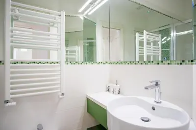 a white bathroom with a sink and a mirror at Elegantis Doris Suite Apartment - One Minute Walk to Vatican Museums in Rome