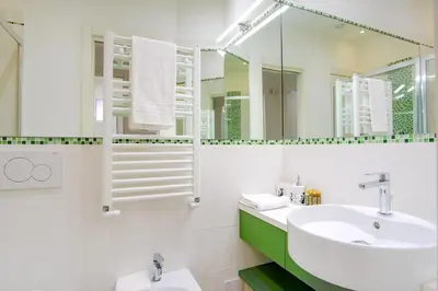 a white bathroom with a sink and a mirror at Elegantis Doris Suite Apartment - One Minute Walk to Vatican Museums in Rome
