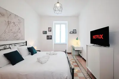 a bedroom with a white bed and a tv on a dresser at Tuscolana Station - 10 minutes from Metro A in Rome