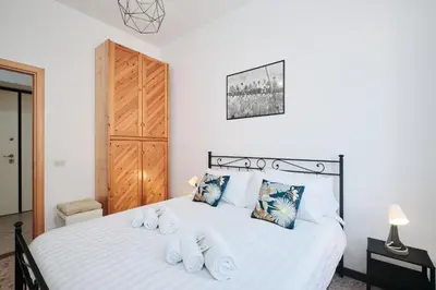 a bedroom with a bed with white sheets and blue pillows at Tuscolana Station - 10 minutes from Metro A in Rome