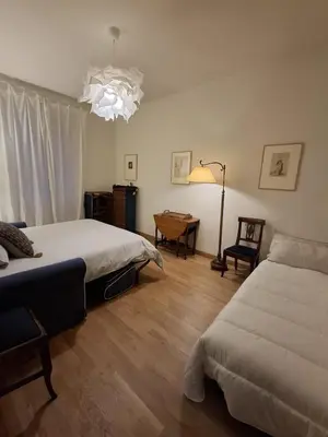 a bedroom with two beds and a table and a chandelier at Appartamento viale Mazzini in Rome