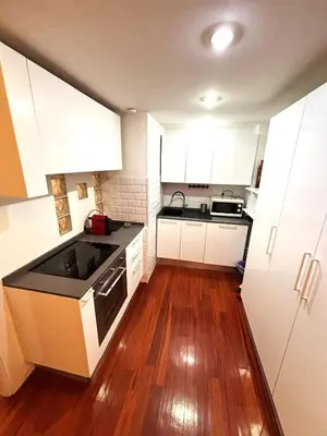 a small kitchen with white cabinets and a wooden floor at Vatican Home - San Pietro - Near to Metro A in Rome