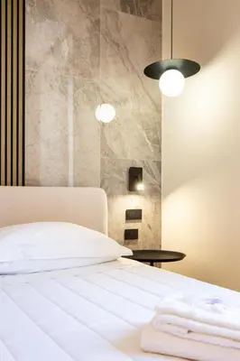 a bedroom with a white bed and a stone wall at Minerva Boutique Suites in Rome