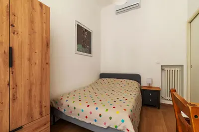 a small bedroom with a bed and a wooden cabinet at GuestHost - Roma Termini Lovely Flat in Rome