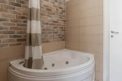 a bath tub in a bathroom with a brick wall at GuestHost - Roma Termini Lovely Flat in Rome
