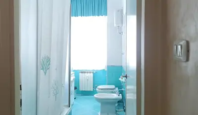a bathroom with a toilet and a blue tile floor at A casa di Ugo - Colors and space at Pigneto, Rome in Rome