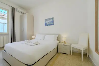 a white bedroom with a white bed and a chair at Operetta View Apartment in Rome