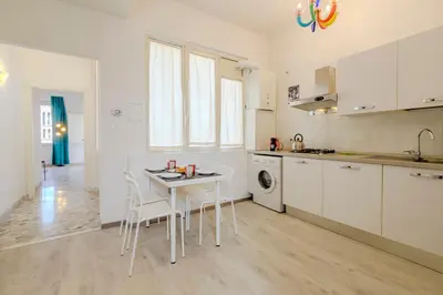 a kitchen with white cabinets and a table and chairs at Operetta View Apartment in Rome