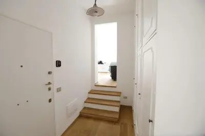 a hallway with white walls and wooden stairs at Colosseum Panoramic Terrace in Rome