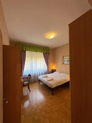 a bedroom with a bed and a chair and a window at St Peter Rooms with Private Parking by Dama in Rome