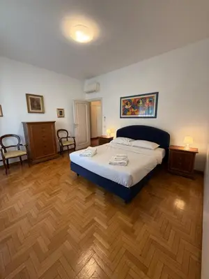a bedroom with a large bed and wooden floors at St Peter Rooms with Private Parking by Dama in Rome