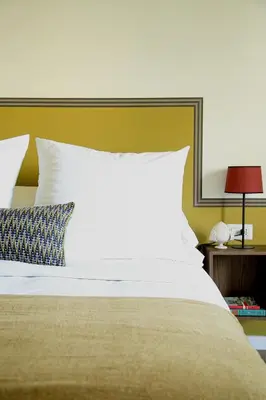 a bed with a white pillow and a yellow wall at Flowers Rooms - Ponte Milvio in Rome