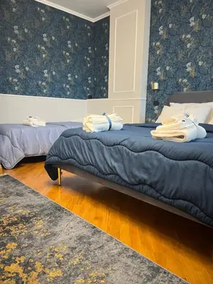 two beds in a bedroom with blue wallpaper at Luxury House Alessia in Rome