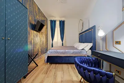 a bedroom with a bed and two blue chairs at Just Chilling Ferruccio in Rome