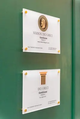 two white signs on a green wall with a sign for a dbi crest at Dei Greci Guesthouse in Rome