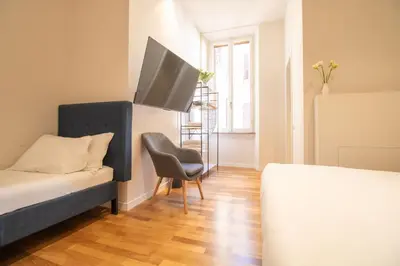 a bedroom with a bed and a chair and a tv at Cunabu Emilio in Rome