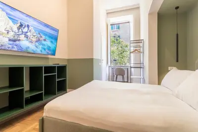 a bedroom with a large white bed and a flat screen tv at Cunabu Emilio in Rome