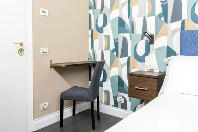 a bedroom with a desk and a chair next to a bed at Maison dei Greci in Rome