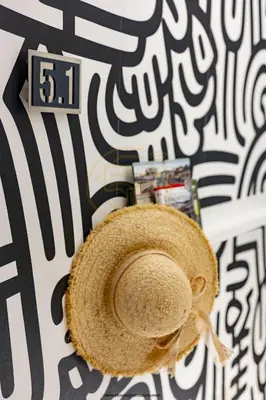 a straw hat sitting on a bed with a clock at cinquepuntozero in Rome