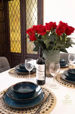 a table with a vase of red roses and a bottle of wine at Aurelian Crown Central Rome in Rome