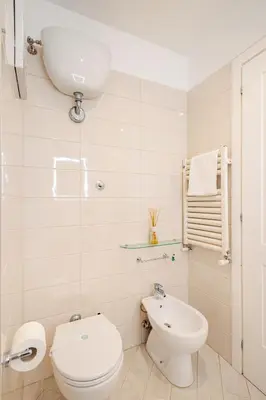 a white bathroom with a toilet and a sink at Aurelian Crown Central Rome in Rome