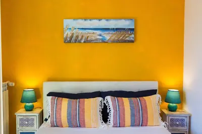 a bedroom with an orange wall and a bed with two lamps at Boutique Domus Trastevere Family in Rome