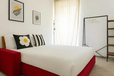 a bedroom with a white bed and a red chair at Ospiti di Jole al Pigneto in Rome