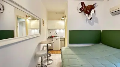 a living room with a green couch and a kitchen at Tiny Elephant Mini suite in Rome in Rome