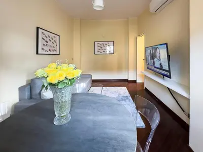 a vase with yellow flowers on a table in a living room at Casa Anna Vaticano in Rome