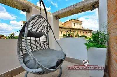a hanging chair on a balcony with a building at Terrazza Marco Antonio Luxury Suite in Rome