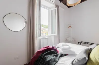 a bedroom with a bed with a mirror and a window at Fienaroli in Trastevere in Rome