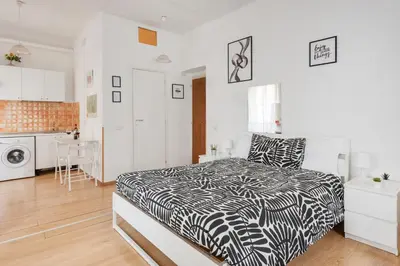 a bedroom with a black and white bed and a kitchen at Studio basic nice&comfortable in Rome