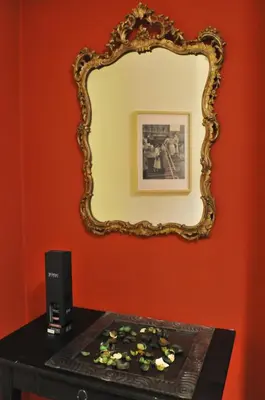 a mirror on a red wall next to a table with a speaker at Celio west side apartment in Rome